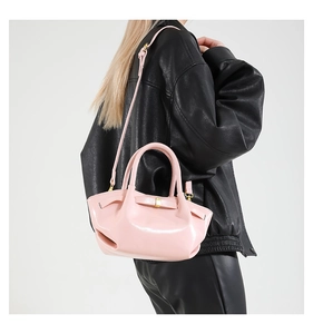 Close-up of pink wax leather pleated bucket bag with gold buckle on a black leather jacket