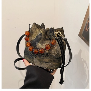 Detail of butterfly embroidery on bucket bag with amber beaded handle and drawstring