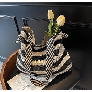 Détail du sac cabas tissé à rayures noires et blanches posé sur une chaise en bois
