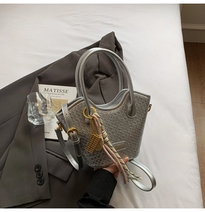 Detail of silver woven bucket bag with metal abacus charm and decorative silk scarf