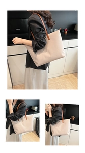 Detail of large nylon tote bag featuring brown slim handles and side metal logo plaque