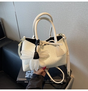 Detail of white crocodile texture tote bag with floral charm and detachable strap