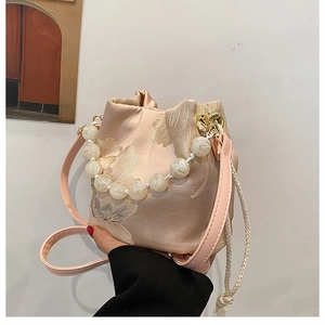 Detail of champagne pink bucket bag with floral embroidery and white pearl beaded handle