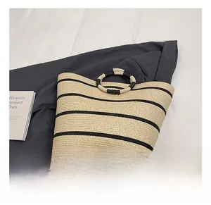Macro detail of natural straw weave texture and black striped pattern on beach tote bag
