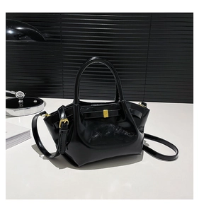 Détails du cuir verni noir brillant avec boucle dorée sur un sac à bandoulière chic
