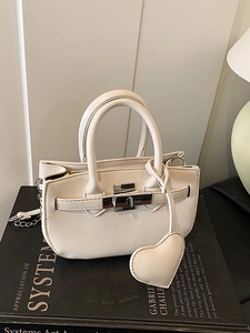 Chic cream mini shell handbag with silver twist lock and heart charm on books