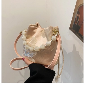 Detail of floral embroidery and pearl handle on apricot pink silk bucket bag