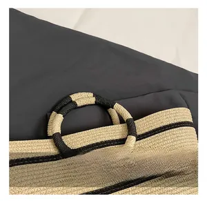 Detail of round woven handle with black and white twine on a summer straw bucket bag