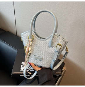 Detail of light blue woven bucket bag with gold hardware and pink rope charm