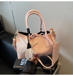Pink woven bucket bag featuring dual handles, white flower charm, and matching small pouch