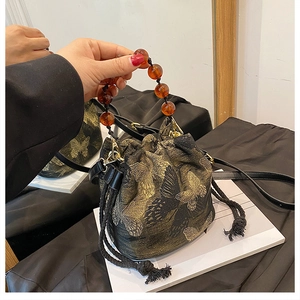 Detail of butterfly embroidered bucket bag with amber bead handle and drawstring