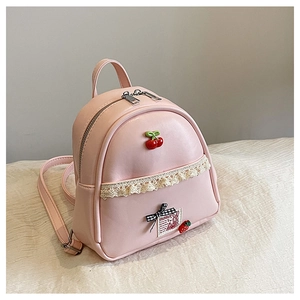 Detail van een schattige roze mini rugzak met kant en een kersenhanger decoratie