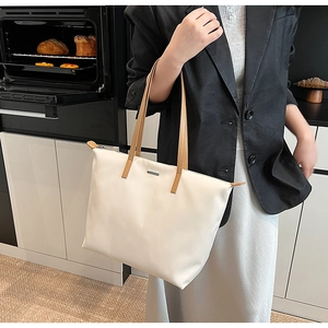 Detail of cream tote bag with brown straps shown in a modern lifestyle setting
