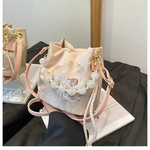Close-up of pink bucket bag with peony embroidery and elegant pearl beaded handle