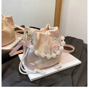 Detail of pink satin bucket bag with floral embroidery and white pearl beaded handle