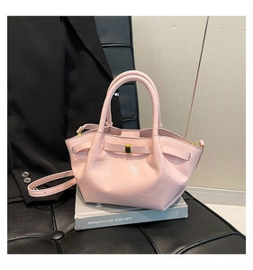 Détail d'un sac moto en similicuir rose avec ferrures dorées sur un support de décor