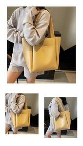 Detail view of large cream leather tote bag featuring functional front pocket and dual handles