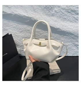 Détail d'un sac à main en cuir verni crème avec plis latéraux et boucles dorées