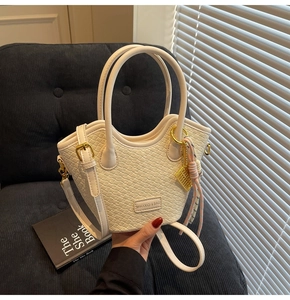 Detail of woven texture on white crossbody bucket bag with golden abacus charm