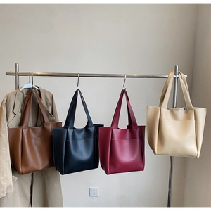 Four minimalist large tote bags in brown, black, burgundy, and beige on a display rack