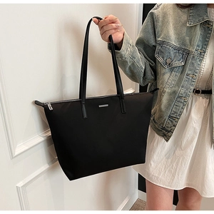 Detailed macro view of the black nylon tote bag with silver metal trim and zipper