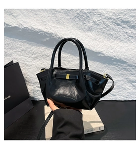 Détail d'un sac moto noir brillant en PU avec nœud papillon et boucles dorées