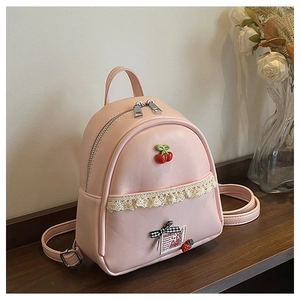 Roze mini rugzak van PU-leer met kant en kersendecoratie op een houten tafel