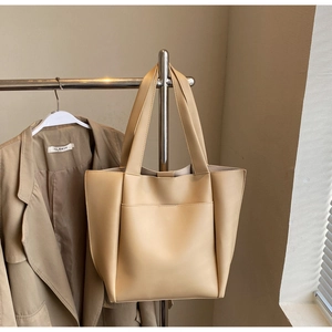 Detailed close-up of a beige tote bag with smooth texture and functional front pocket