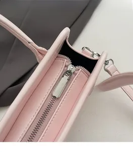 Detailed close-up of smooth silver metal zipper and neat edge stitching on pink leather bag