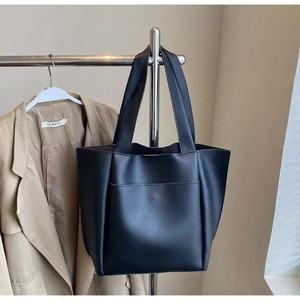 Detail view of black PU leather tote bag showing the front pocket and long shoulder straps