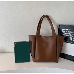 Brown faux leather tote bag with front pocket showing size comparison with a tablet