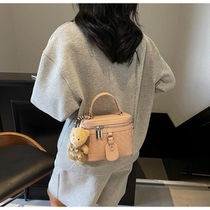 Rosafarbene gesteppte Kastenhandtasche mit Kette und Bärenanhänger an einem Frauenmodel