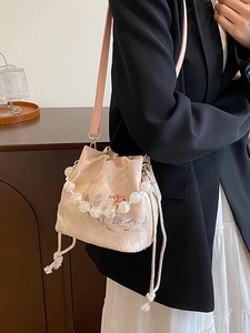 Pink satin bucket bag with floral embroidery and pearl handle shown on a model