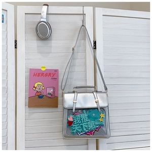 Detail view of a silver ita bag with clear window featuring decorative anime heart badges