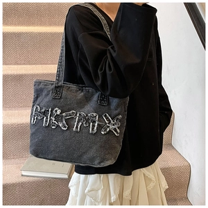 Detail of grey washed denim tote bag featuring MICPOX letter patch on shoulder strap