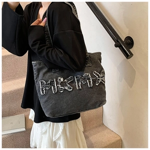 Street style view of washed black denim tote bag with distressed MAMX letter design
