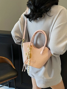 Elegant pink crocodile pattern bucket bag with leaf pendant shown on model