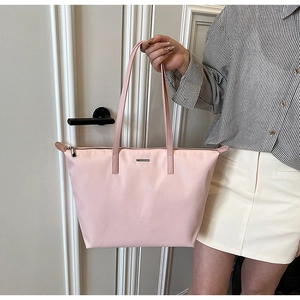 Detailed view of pink nylon tote bag with long handles and metallic logo plate