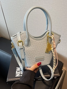 Light blue woven bucket bag with dual handles and gold tennis racket charm detail