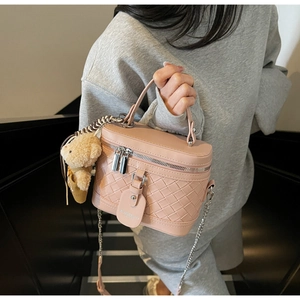 Detailaufnahme der rosa geflochtenen Box-Tasche mit Silberkette und Bärenanhänger
