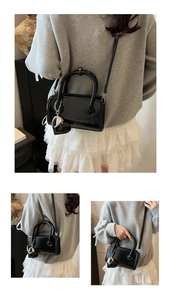 Detail showing shiny black PU leather bowling bag with heart charm and shoulder strap