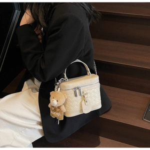 Detail der cremeweißen gewebten Box-Tasche mit silbernen Reißverschlüssen und Bär