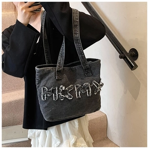 Detail view of retro washed denim tote featuring distressed letter patchwork and zipper