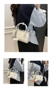 Detail of white PU leather bowling bag showing silver heart charm and crossbody strap