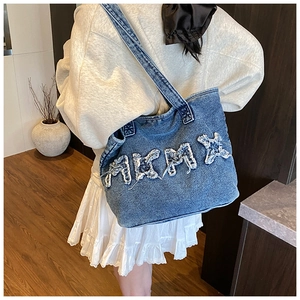 Detail view of the washed denim tote bag featuring distressed letter patches on the side