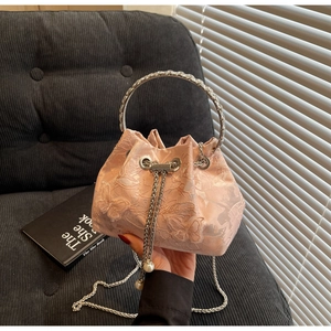 Detail of pink embroidered bucket bag with silver metal handle and pearl drawstring charms