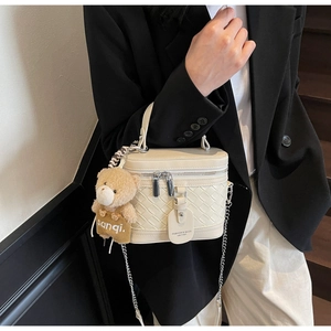 Detail der cremefarbenen gewebten Box-Tasche mit Metallkette und Bären-Anhänger