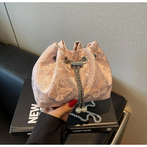 Detailed view of pink drawstring bucket bag with butterfly embroidery and pearl chain