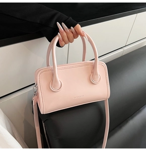 Detail of light pink rectangular handbag with CLEAROK embossed logo and top handle