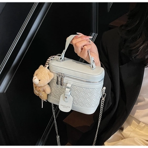 Nahaufnahme der hellblauen geflochtenen Ledertasche mit Bärenanhänger und Kettenriemen